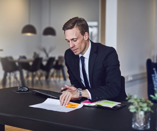 Businessman catching up on paperwork at his office desk Businessman sitting alone at his desk and going over notes and paperwork while working in an office